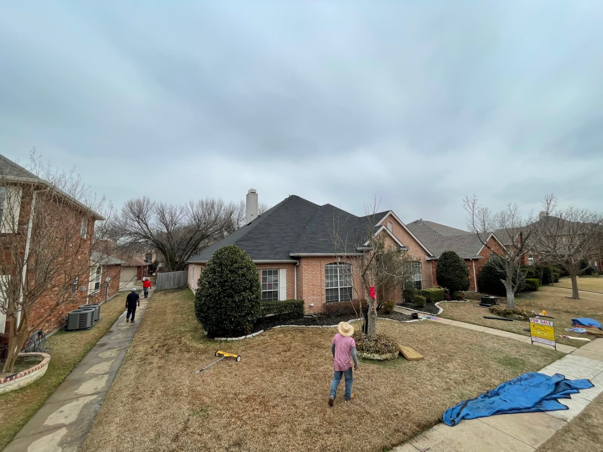 Homebase Roofing crew mid tear-off on a single-story brick home in the North Dallas area, with a magnetic nail sweeper on the lawn and tarps staged at the curb